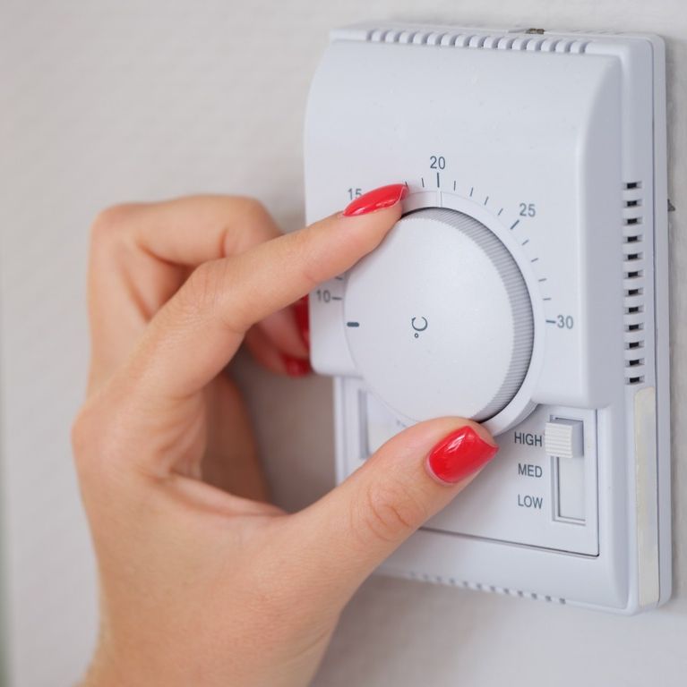 mano de mujer grirando termostato